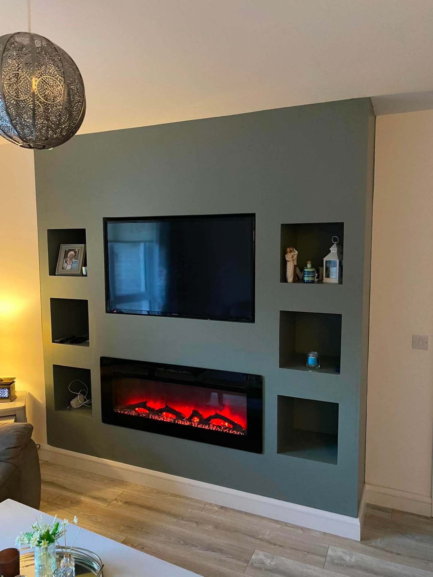 Sage green feature media wall with electric fire, TV and alcove niches