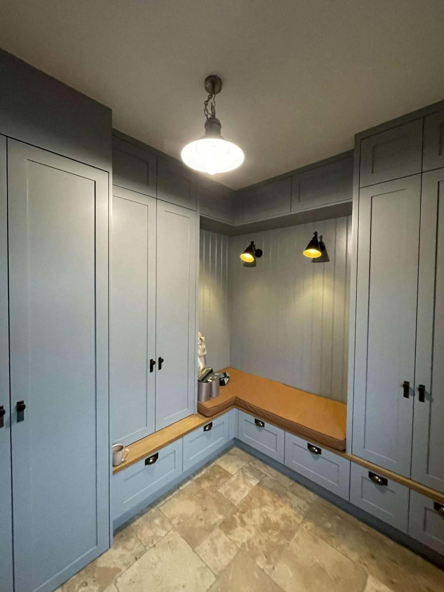 Blue-grey L-shaped utility with shaker tall cabinets, oak bench top and vintage pendant lighting